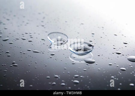 Le lenti a contatto e gocce di acqua su sfondo grigio Foto Stock