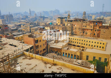 Osservare il vecchio quartiere del Cairo islamico dal tetto con vista sulle case di squallido, cumuli di rifiuti e fumoso sagome di edifici e minareti su Foto Stock