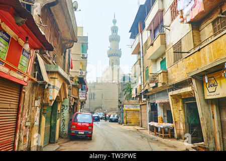 Il Cairo, Egitto - 22 dicembre 2017: a piedi la meschina El Darb El Ahmar street con una vista sulla storica Amir Al-Maridani moschea in luce winter haze, su Dec Foto Stock