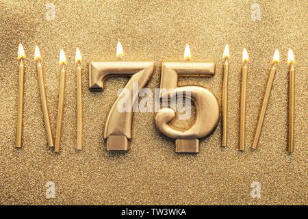 Numero 75 celebrazione oro candela su un sfondo glitter Foto Stock