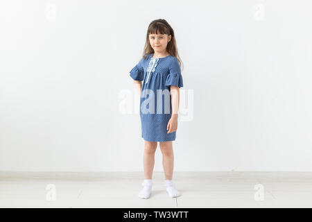 Bambino adorabile ragazza in vestito blu su sfondo bianco Foto Stock