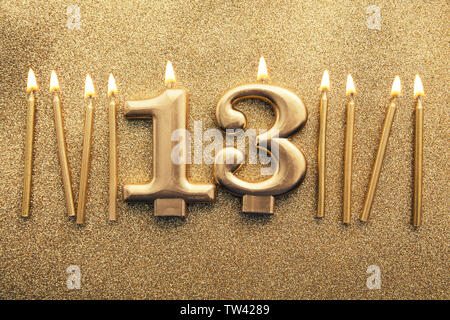 Numero 13 celebrazione oro candela su un sfondo glitter Foto Stock