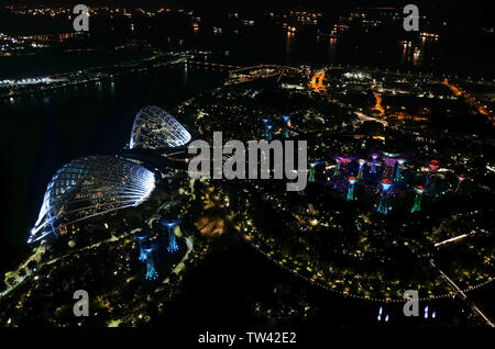 Vista aerea scattata di notte tempo da Marina Bay hotel guardando in giù verso i giardini dalla Baia di Singapore. Foto Stock