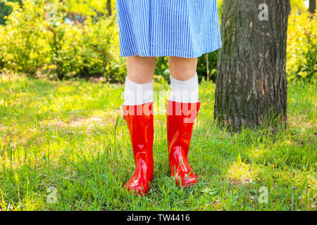 Giovane donna in rosso gli stivali da pioggia all'aperto Foto Stock