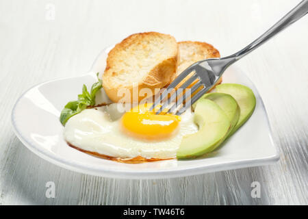 Mangiare deliziosa oltre il semplice uovo con toast e avocado sul tavolo da cucina Foto Stock