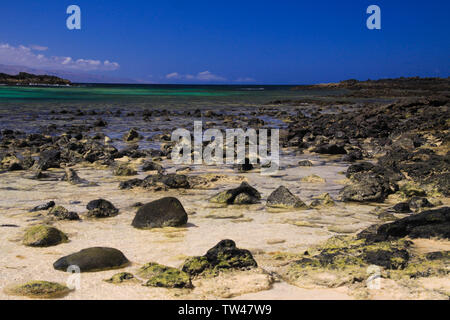 El Cotillo, Nord Fuerteventura: Vista su luminose sparse stoneson beach in acque poco profonde sulla laguna turchese della spiaggia della Concha contro deep blue s Foto Stock