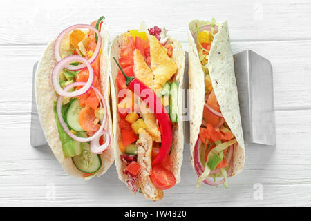 Cavalletto con il gustoso pesce tacos bianco su sfondo di legno Foto Stock