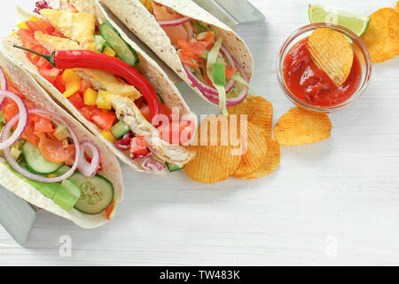 Cavalletto con il gustoso pesce tacos bianco su sfondo di legno Foto Stock