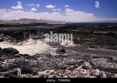 El Cotillo - Faro del Toston: Vista su nere rocce vulcaniche e sulla laguna village dalla spiaggia della Concha nord Fuerteventura Foto Stock