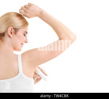 Bella giovane donna utilizzando deodorante su sfondo bianco Foto Stock