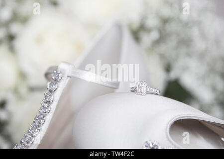 Brides anello di fidanzamento seduto sulla parte superiore del suo giorno di nozze scarpa, white satin diamante cassone nuziale, in attesa di essere indossato il giorno delle nozze. Foto Stock