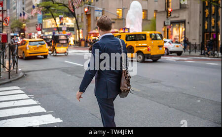 Stati Uniti, New York. Il 3 maggio 2019. Youmg imprenditore in abito scuro con un sacchetto di cuoio camminando nelle strade di Manhattan, Primavera, pomeriggio Foto Stock