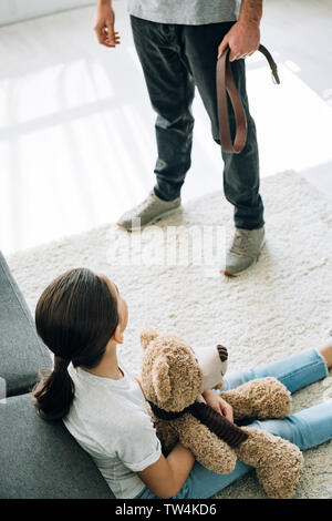 Vista aerea del padre con la cinghia e la figlia seduta sul pavimento Foto Stock