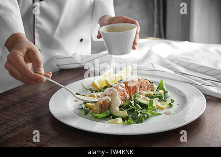 Lo chef femmina salsa di colata sulla piastra con deliziosi salmone in cucina Foto Stock