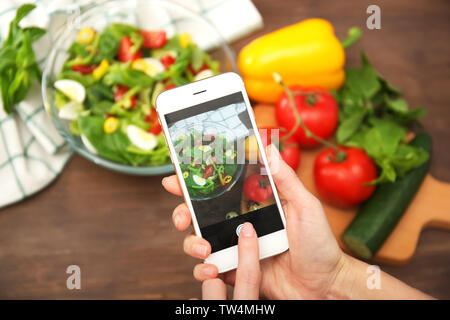 Mani femminili prendendo foto di alimenti con il telefono cellulare Foto Stock