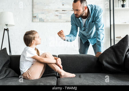Padre arrabbiato che minacciano con pugno e di stare vicino a sconvolgere la figlia a casa Foto Stock