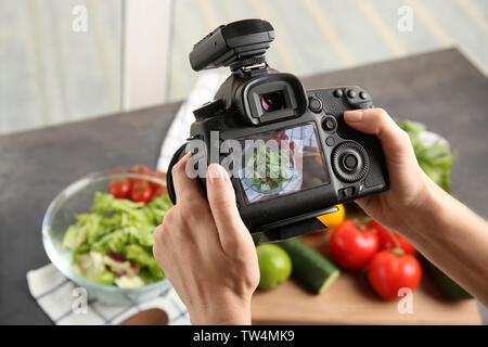 Donna prendendo foto di cibo con telecamera professionale Foto Stock