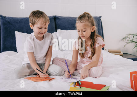 Carino kids rendendo padri giorno saluto automobili mentre seduto sul letto a casa Foto Stock