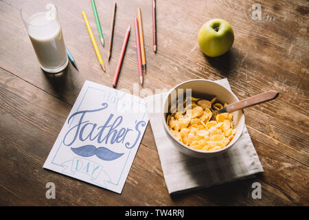 Padri giorno biglietto di auguri, matite multicolori, ciotola con fiocchi, fresh apple e un bicchiere di latte sul tavolo in legno Foto Stock