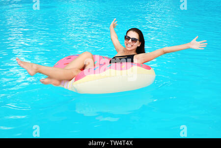 Bella giovane donna sulla ciambella gonfiabile in piscina Foto Stock