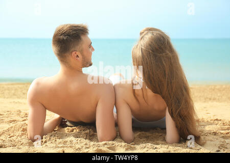 Felice coppia giovane sdraiato sulla spiaggia Foto Stock