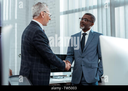 Basso angolo vista di uomini di affari multiculturali stringono le mani in office Foto Stock