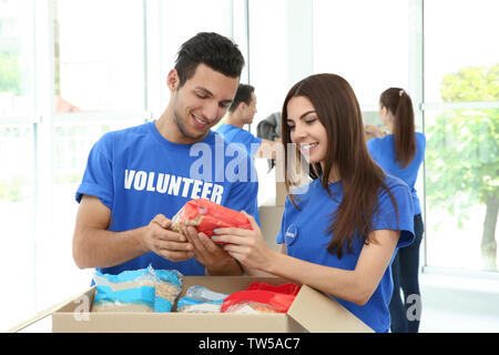 Team di volontari teen la raccolta di donazioni di cibo in scatola di cartone in ambienti interni Foto Stock