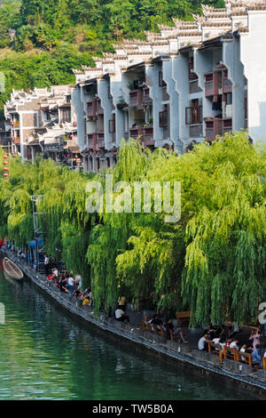 Case tradizionali lungo il fiume Wuyang e gara di dragon boat sul fiume durante il Duanwu Festival, Zhenyuan, Guizhou, Cina Foto Stock