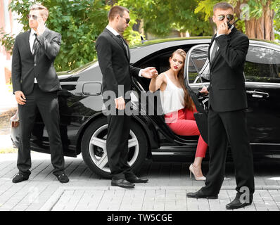 La guardia del corpo aiutando giovane imprenditrice per uscire dall'auto Foto Stock