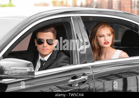 Giovani celebrità con la guardia del corpo in auto moderna Foto Stock
