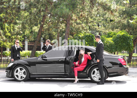 La guardia del corpo aiutando giovane imprenditrice per uscire dall'auto Foto Stock