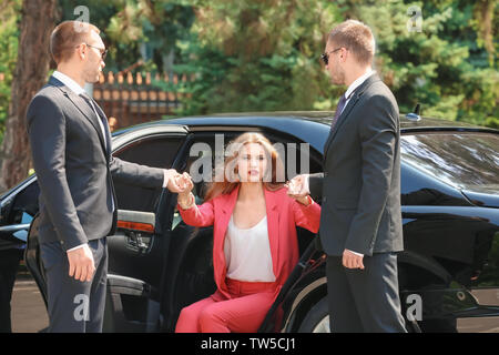 Guardie del corpo aiutando giovane imprenditrice per uscire dall'auto Foto Stock