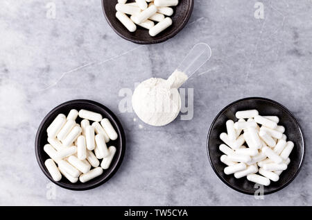 Scoop di proteina di siero di latte, idrolizzati di collagene di tipo I, L-prolina e L-lisina capsule. Supplementi per supportare la produzione di collagene. Foto Stock