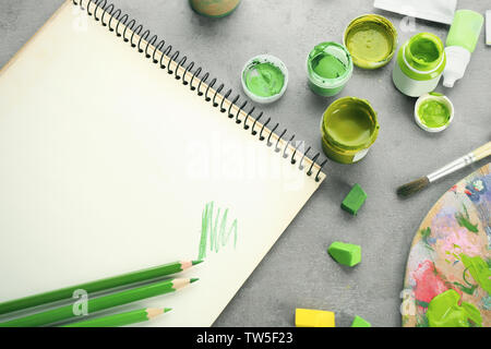 Composizione con matite di colore verde, notebook e i gessi su tavola Foto Stock
