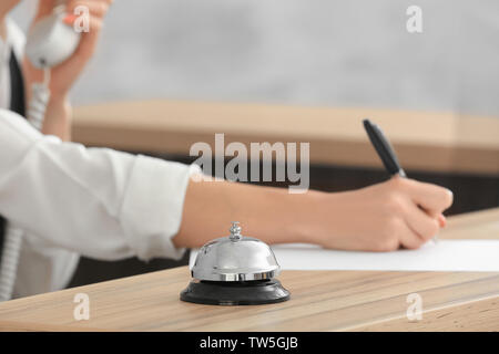 Campana di servizio sulla scrivania e sfocata receptionist in hotel Foto Stock