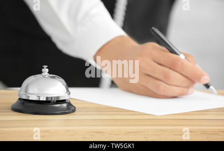 Campana di servizio sulla scrivania e sfocata receptionist in hotel Foto Stock