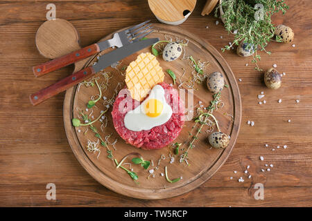 Deliziosa la tartare di manzo con uovo e wafer sul pannello di legno Foto Stock