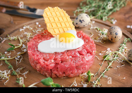 Deliziosa la tartare di manzo con uovo e wafer sul pannello di legno Foto Stock