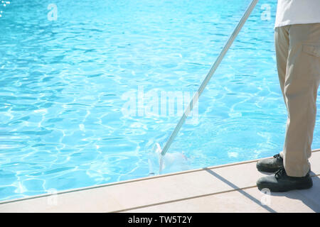 L'uomo la pulizia piscina con scoop net Foto Stock