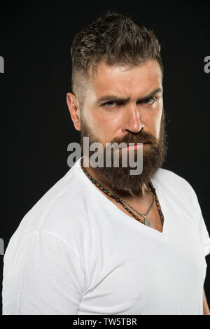 Capelli tendenze di design. Grave hipster con lunga barba e capelli elegante su sfondo nero. Uomo Barbuto con barba lunga capelli viso. Brutale guy sagomato con barba e baffi Peli. Foto Stock