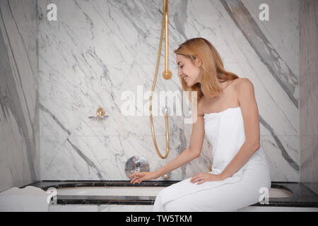 Bella giovane donna seduta nella stanza da bagno Foto Stock
