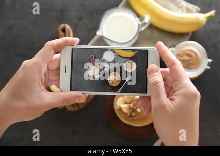 Donna prendendo foto di cibo delizioso con il telefono cellulare Foto Stock