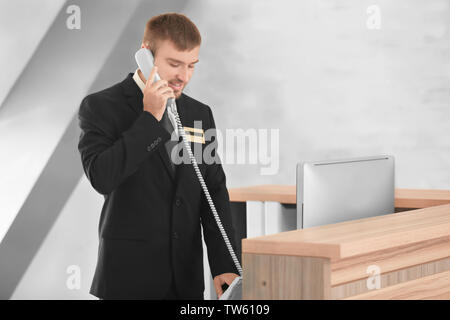 Receptionist maschio parlando al telefono in hotel Foto Stock