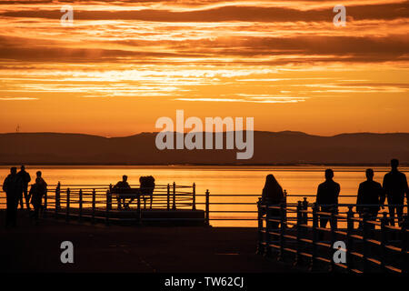 Trafalgar Piont, Morecambe, Lancashire, Regno Unito, 18 giugno 2019 visitatori guardare il sole andare giù dalla fine del molo di pietra conosciuta come Trafalgar Piont. Credito: fotografare Nord/Alamy Live News Foto Stock