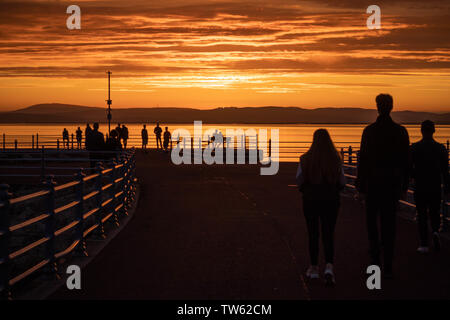 Trafalgar Piont, Morecambe, Lancashire, Regno Unito, 18 giugno 2019 visitatori guardare il sole andare giù dalla fine del molo di pietra conosciuta come Trafalgar Piont. Credito: fotografare Nord/Alamy Live News Foto Stock