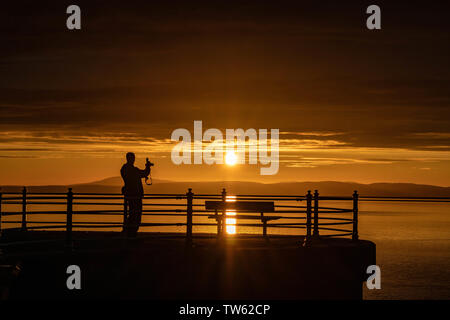 Trafalgar Piont, Morecambe, Lancashire, Regno Unito, 18 giugno 2019 visitatori guardare il sole andare giù dalla fine del molo di pietra conosciuta come Trafalgar Piont. Credito: fotografare Nord/Alamy Live News Foto Stock