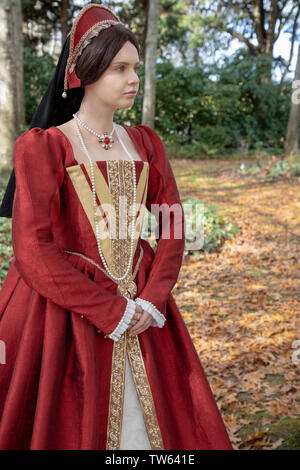 Tudor woman in red dress passeggiate nel giardino Foto Stock
