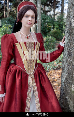 Tudor woman in red dress passeggiate nel giardino Foto Stock