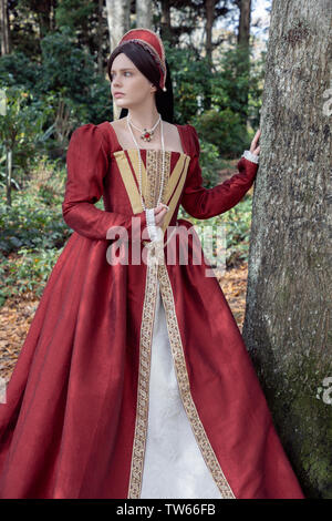 Tudor woman in red dress passeggiate nel giardino Foto Stock