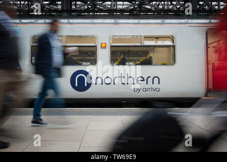 Passeggeri a piedi passato il logo del Nord visto su uno dei treni azienda operativo del materiale rotabile in Manchester Piccadilly. Foto Stock
